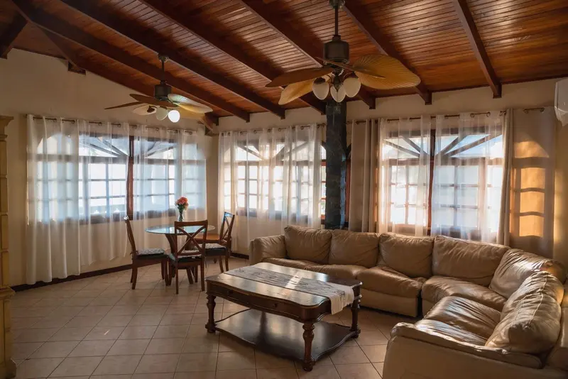 Sala de un condominio con sofá seccional, comedor y techo de madera