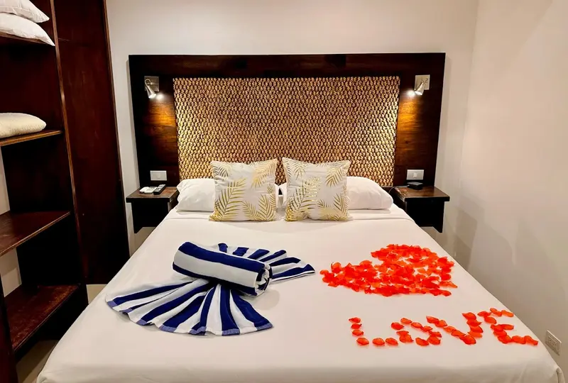 Suite de luna de miel con cama decorada con pétalos de rosa que forman la palabra LOVE y toallas dobladas