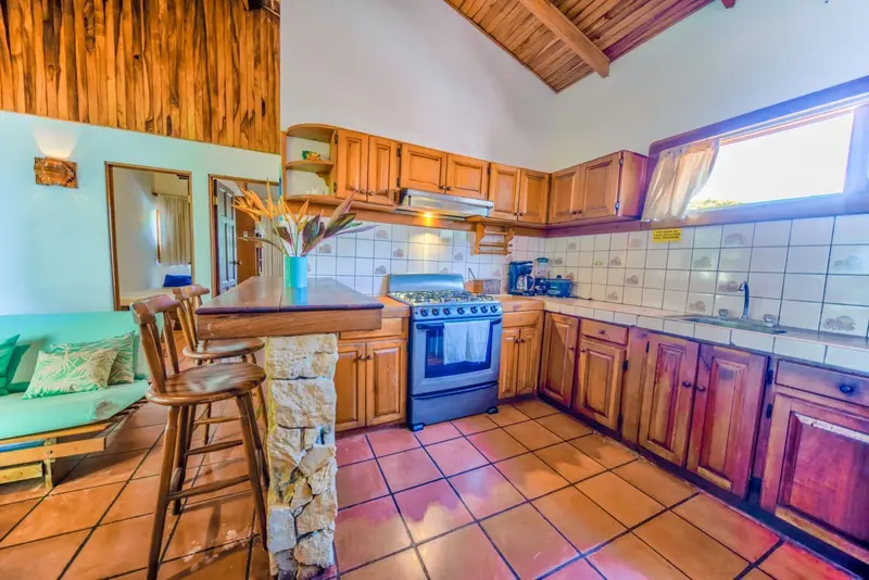 Cocina con estufa azul, gabinetes de madera y barra con taburetes