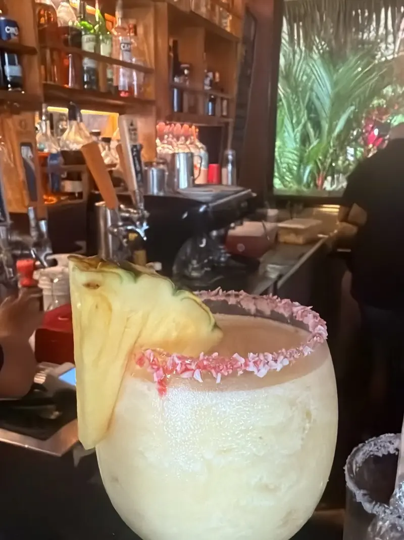 Frozen tropical cocktail with a grilled pineapple wedge and shredded-coconut rim, served at the Vida Hermosa bar