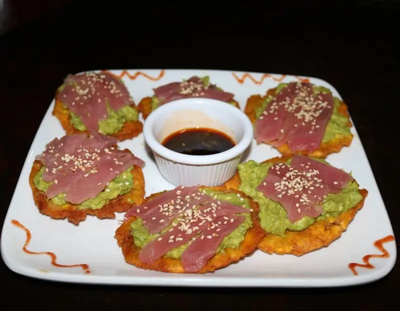 Cuatro patacones con atún, aguacate y ajonjolí, con salsa oscura al centro