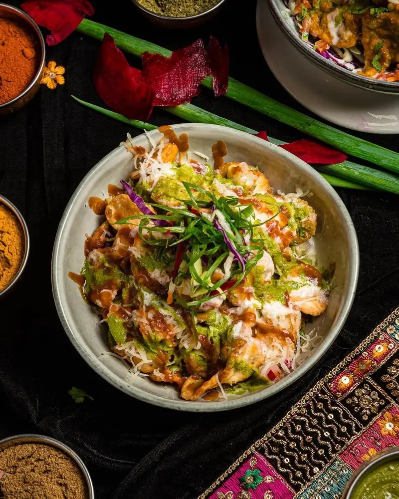 Papri chaat en un cuenco, cubierto de yogur, chutney y cilantro