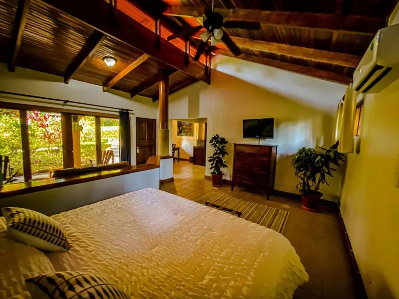 Habitación con cama grande, cielorraso de madera y ventanas al jardín