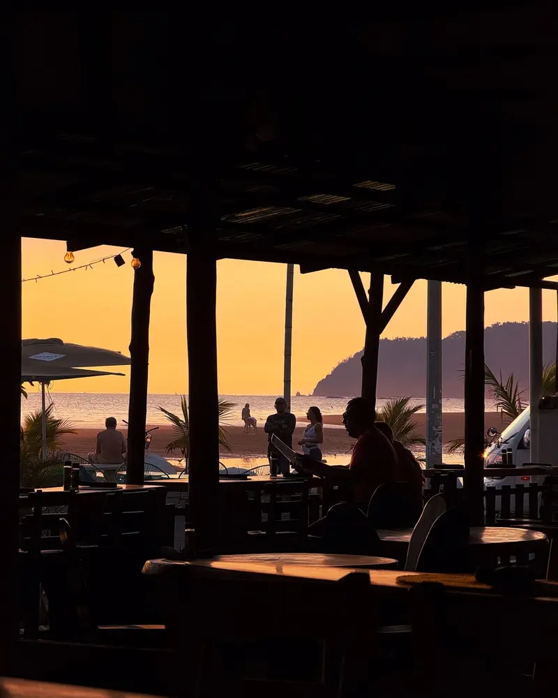 Terraza del restaurante con vista a la playa y las montañas al atardecer