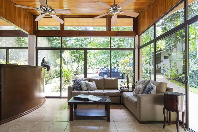 Sala de recepción con sofás y mesa de centro, techo de madera y ventanales hacia el jardín