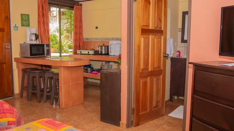 Cocina de un apartamento con barra de madera, taburetes y microondas