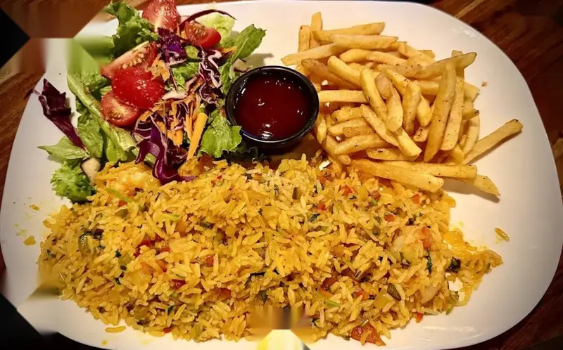 Plato con arroz amarillo, papas fritas, ensalada con salsa roja y vegetales
