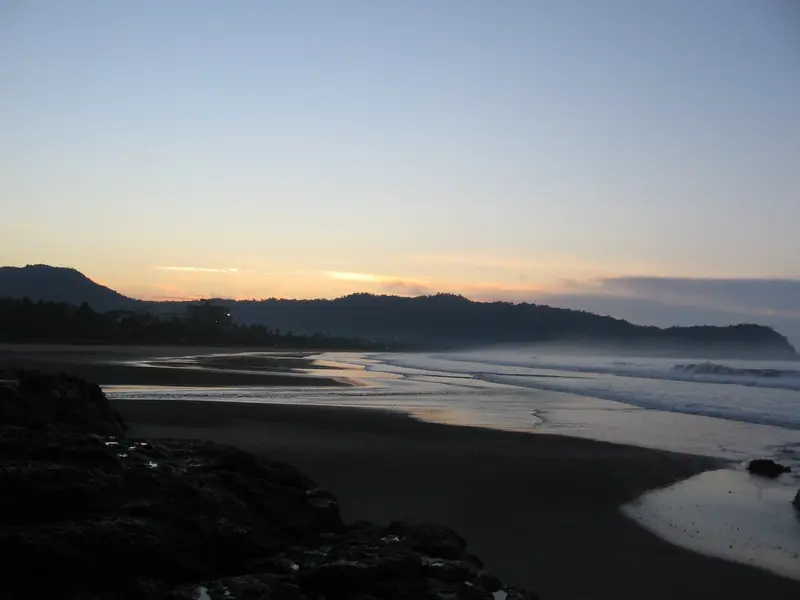 Atardecer sobre la bahía con cielo anaranjado y la silueta de las montañas