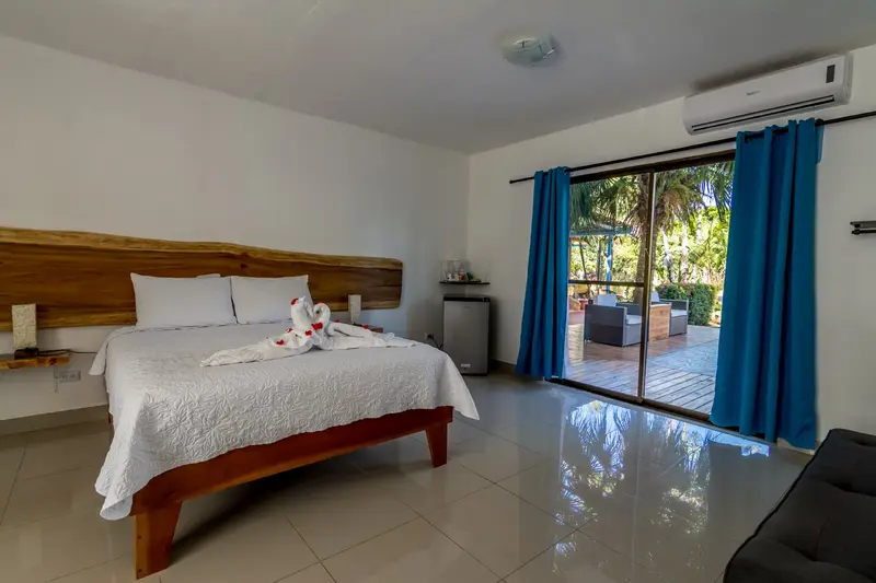 Habitación Deluxe con cama de cabecera de madera, sofá cama y puerta corrediza al jardín