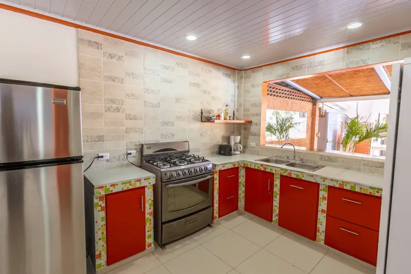 Cocina compartida con barra de madera y taburetes, ventana a la terraza
