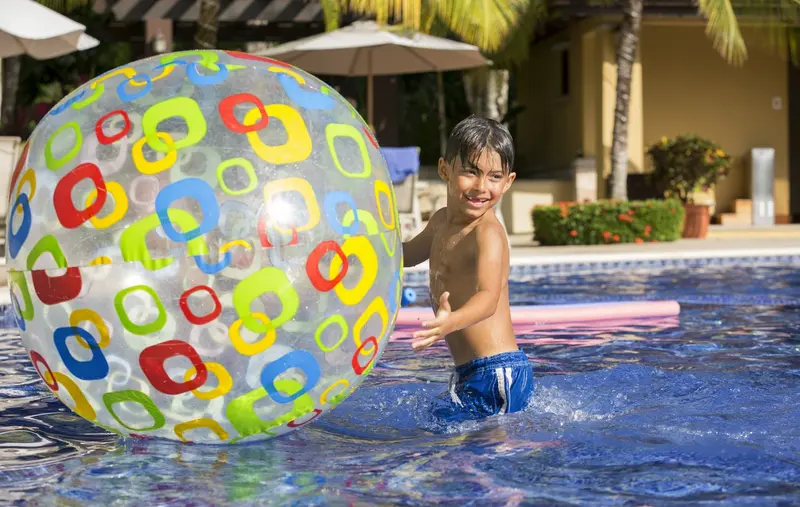 Niño jugando con una pelota inflable en la piscina