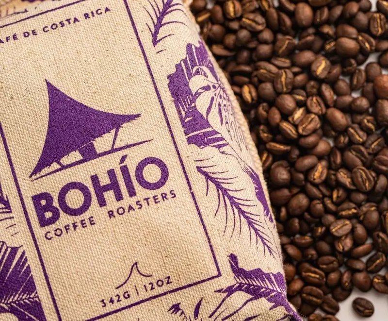 Saco de yute con el logo de Bohío Coffee Roasters junto a granos de café tostados