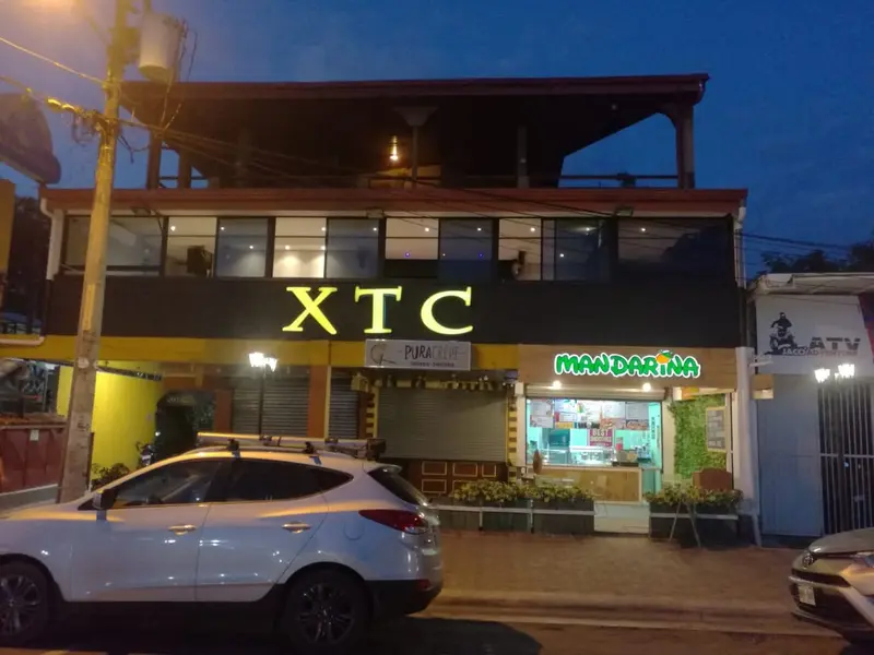 Fachada del local de noche, con el rótulo XTC iluminado sobre la avenida
