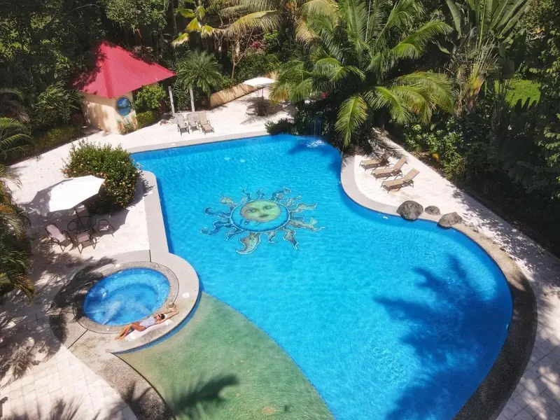 Vista aérea de la piscina con mosaico en el fondo y el jacuzzi, entre la selva