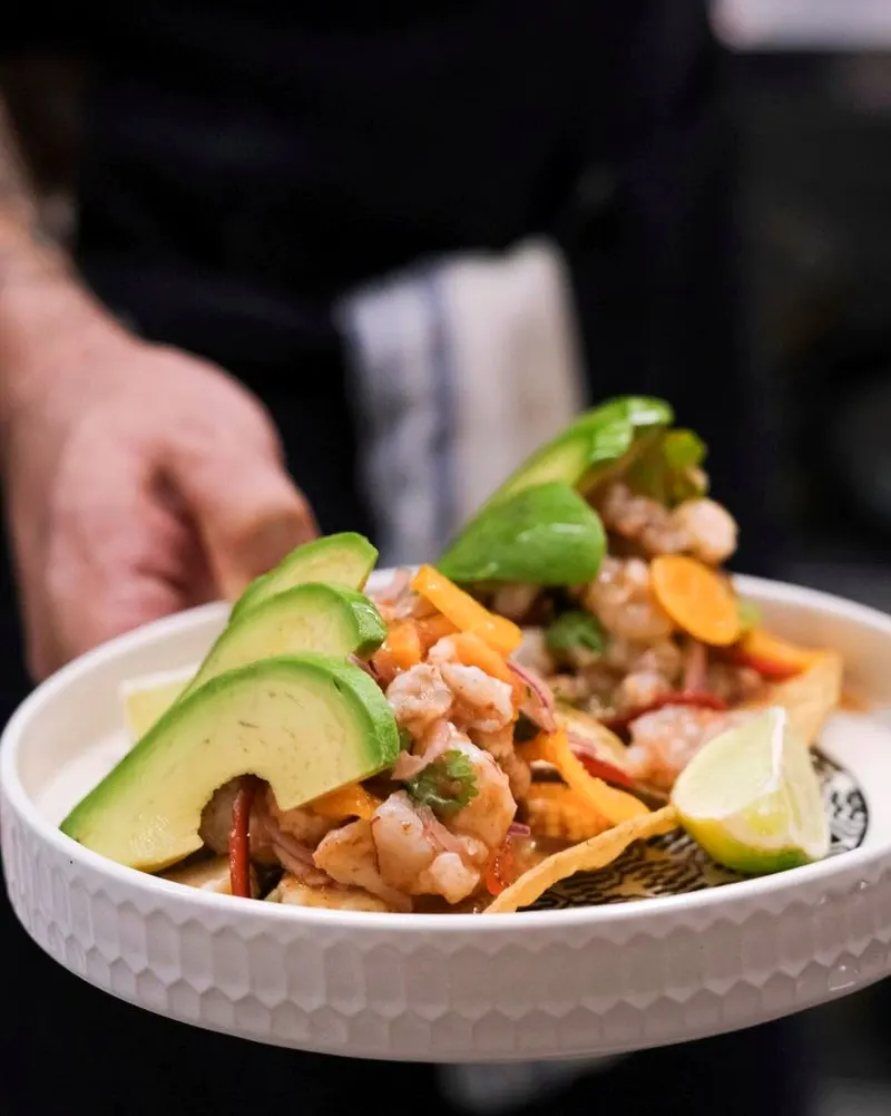White bowl of shrimp ceviche with sliced avocado and lime