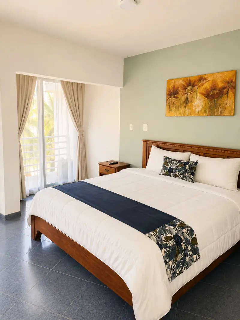 Habitación con cama doble, camino de cama azul marino y puerta al balcón