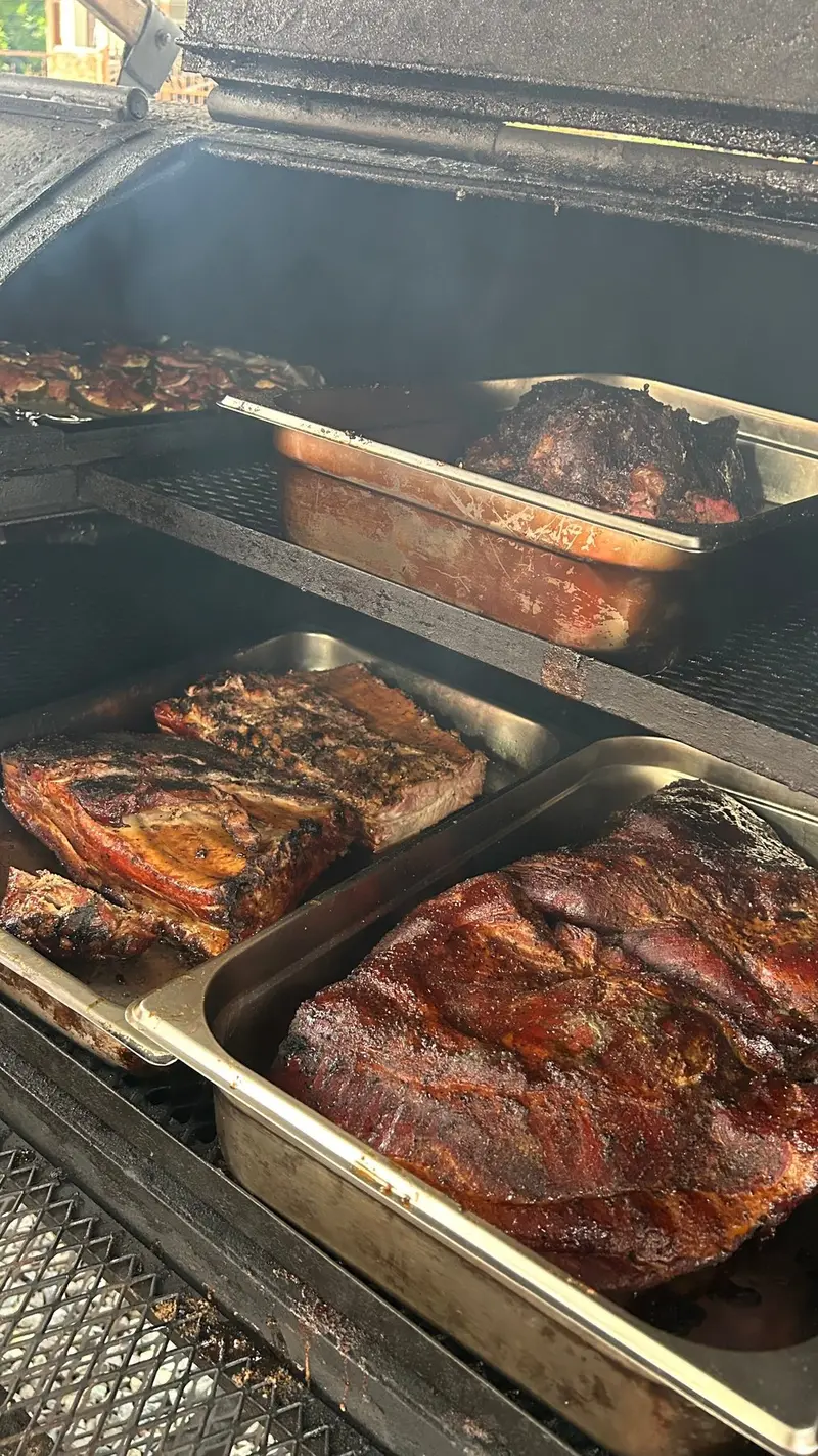 Cortes de carne ahumándose en bandejas dentro del ahumador