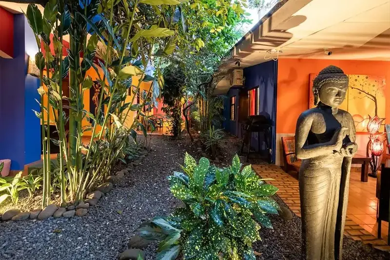 Jardín con una estatua de Buda entre plantas tropicales