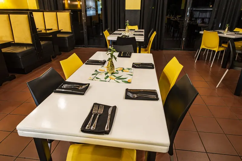 Mesa larga blanca con vajilla y sillas negras y amarillas en el salón