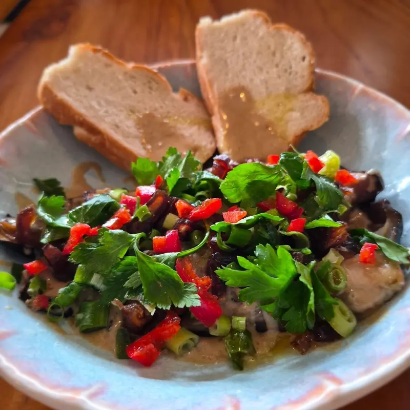 Ensalada con perejil, pimiento rojo y pepino sobre un plato azul, con dos rebanadas de pan