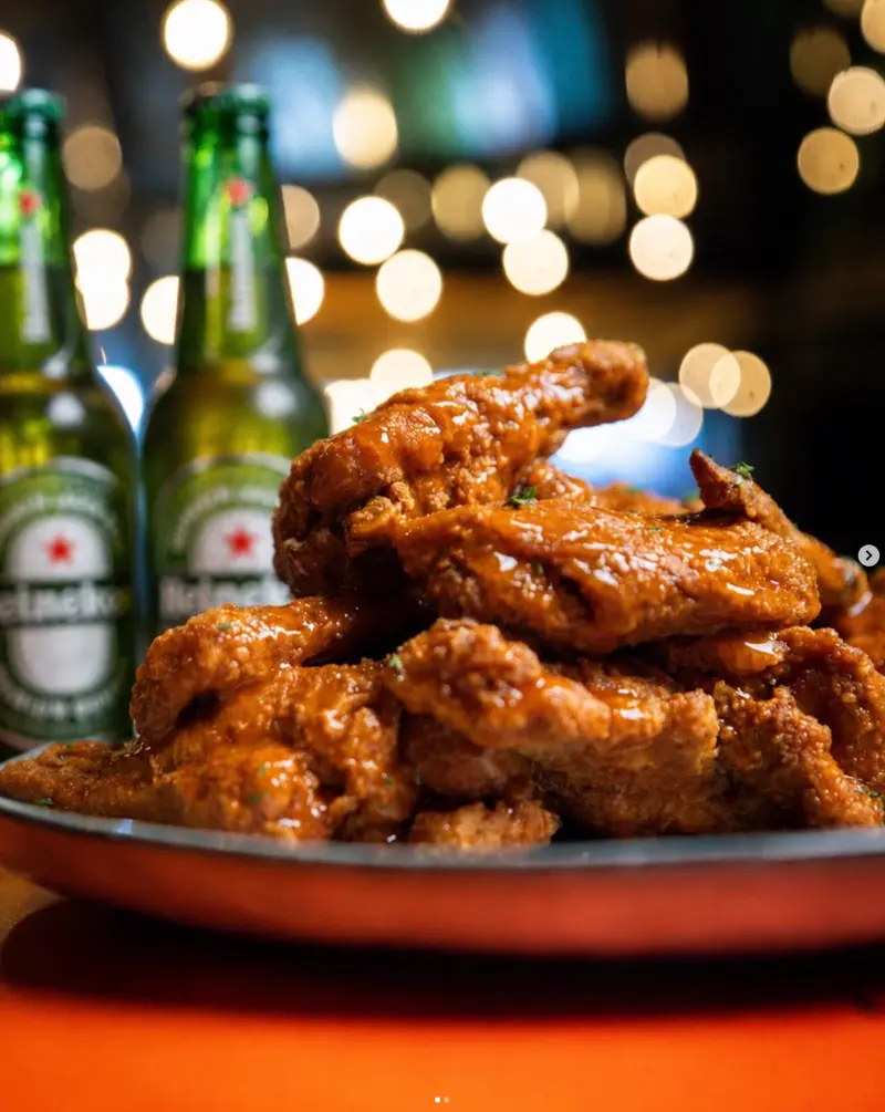 Alitas bañadas en salsa acompañadas de dos cervezas Heineken, en D'Corner