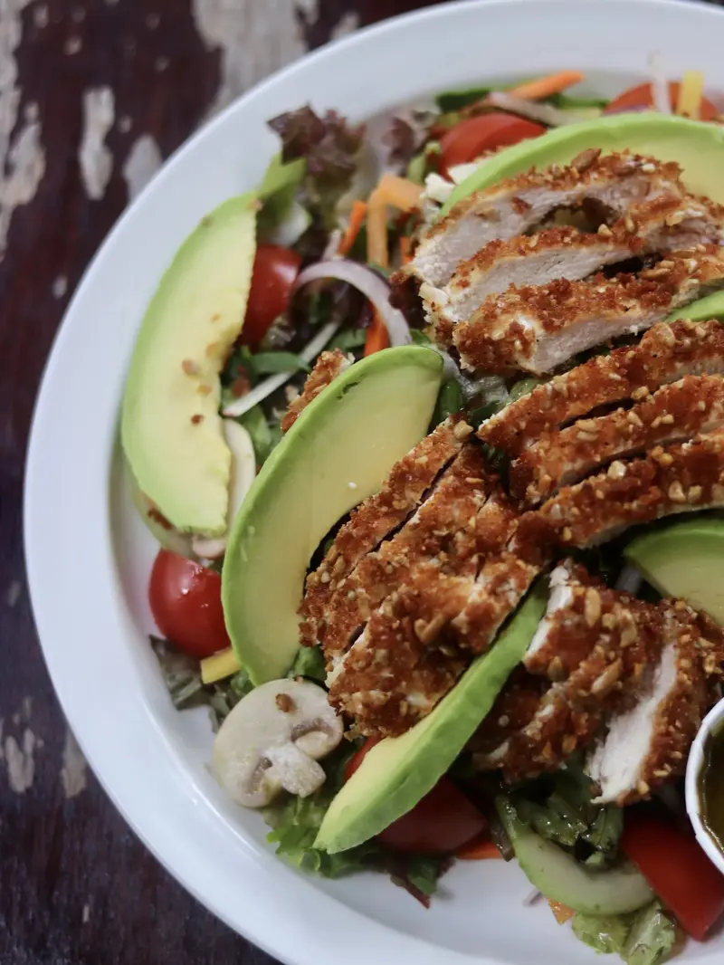 Ensalada con pollo crujiente empanizado, aguacate, tomate cherry y vegetales mixtos