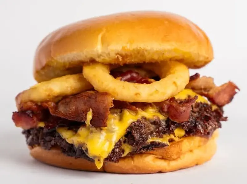 Onion BBQ: doble carne smash, queso americano, tocino y aros de cebolla en pan brioche