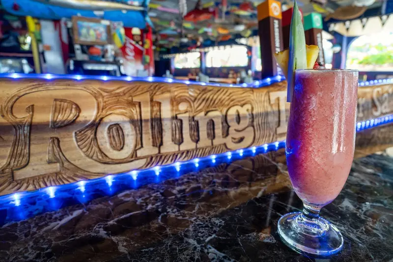 Barra con el letrero tallado Rolling Thunder Saloon y un trago helado rosado en copa