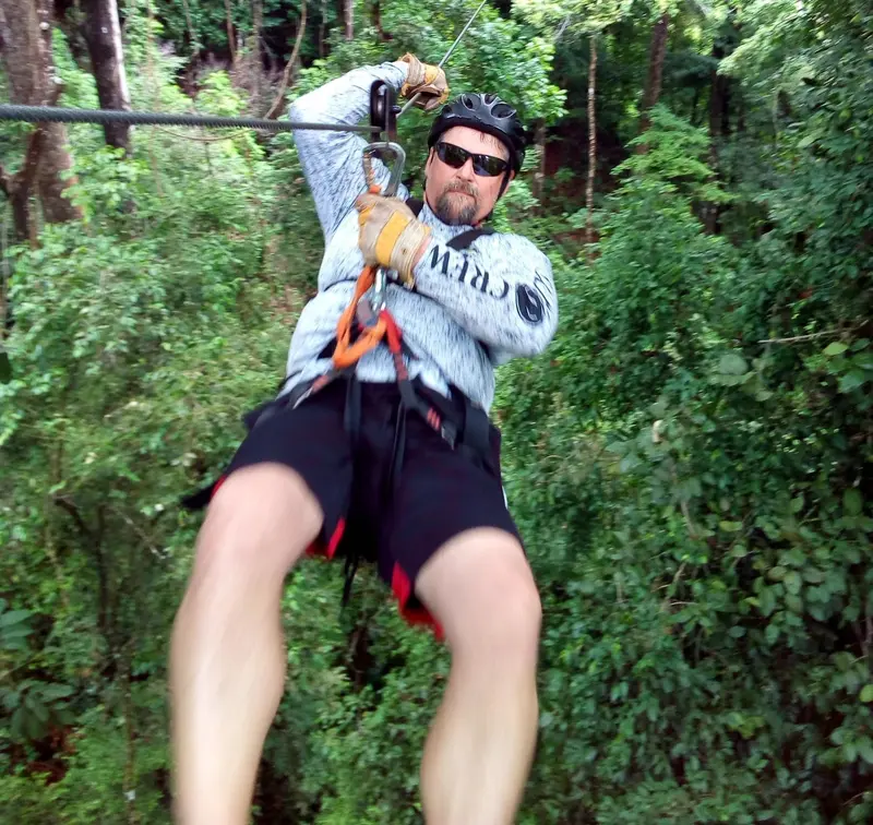 Guest wearing a helmet and harness crossing a zipline