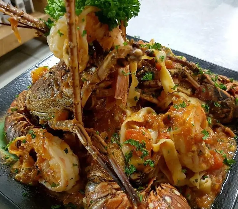 Parrillada de mariscos con langosta, camarones y pasta en salsa roja