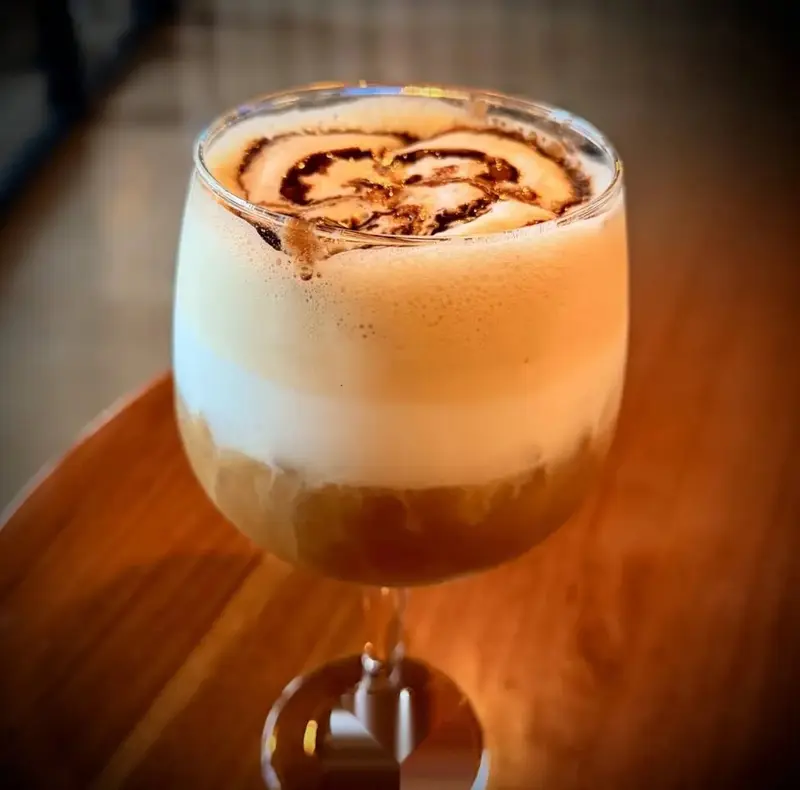 Cóctel cremoso con espuma y dibujo de café servido en copa