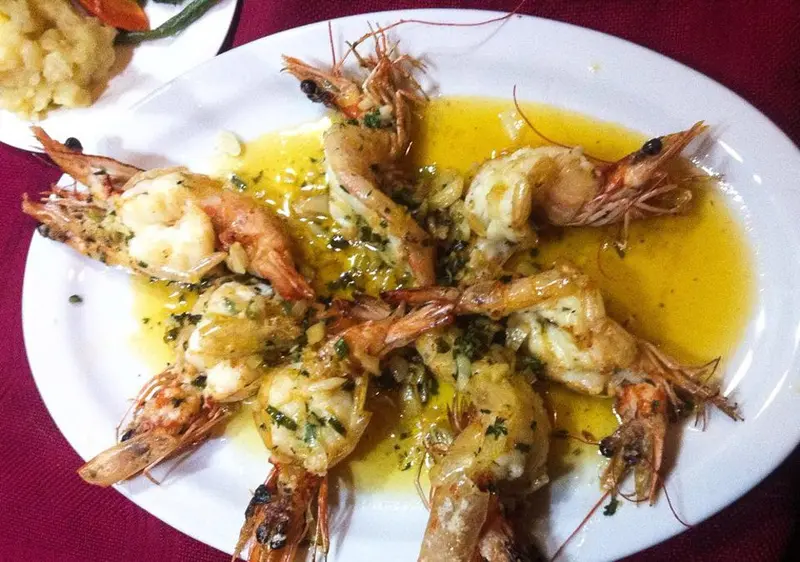Camarones grandes a la mantequilla con ajo sobre un plato blanco