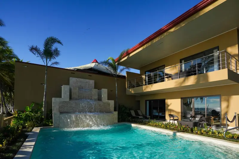 Piscina con una cascada de piedra y las habitaciones de dos pisos con balcones alrededor
