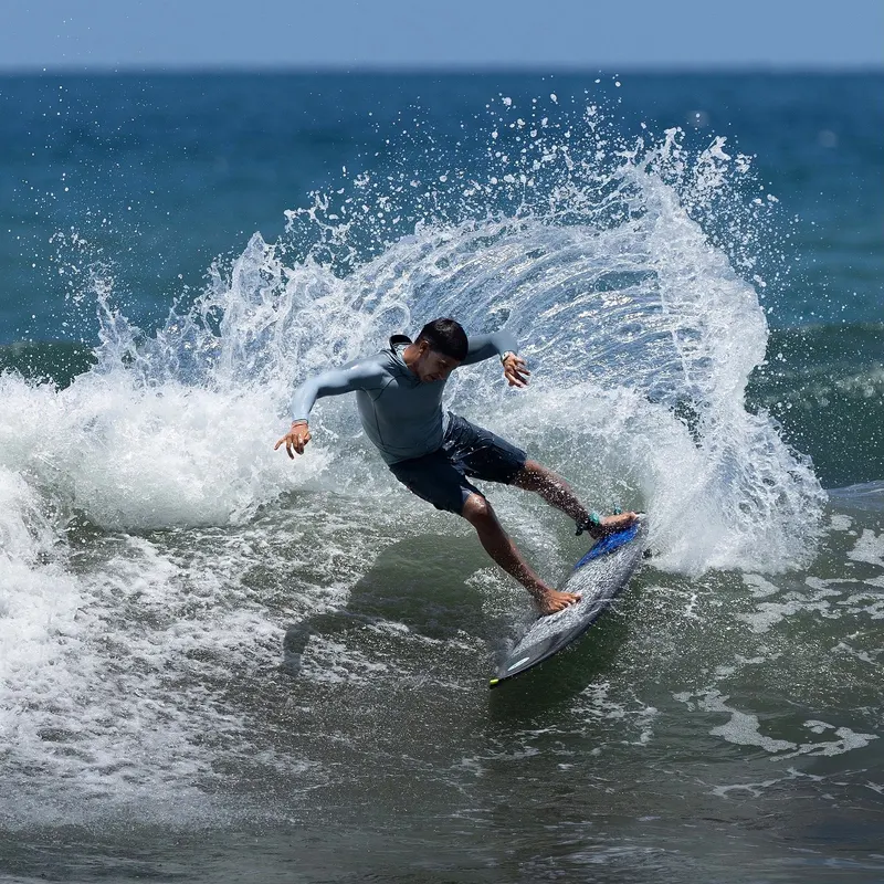 A surfer carving a turn on a wave, with a large spray of water behind the board