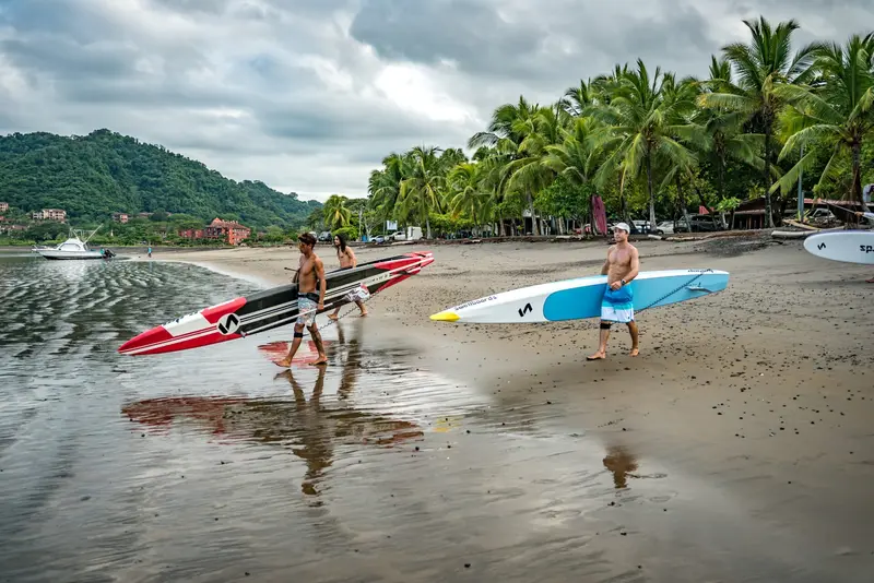 Remadores caminando por la playa con tablas de SUP