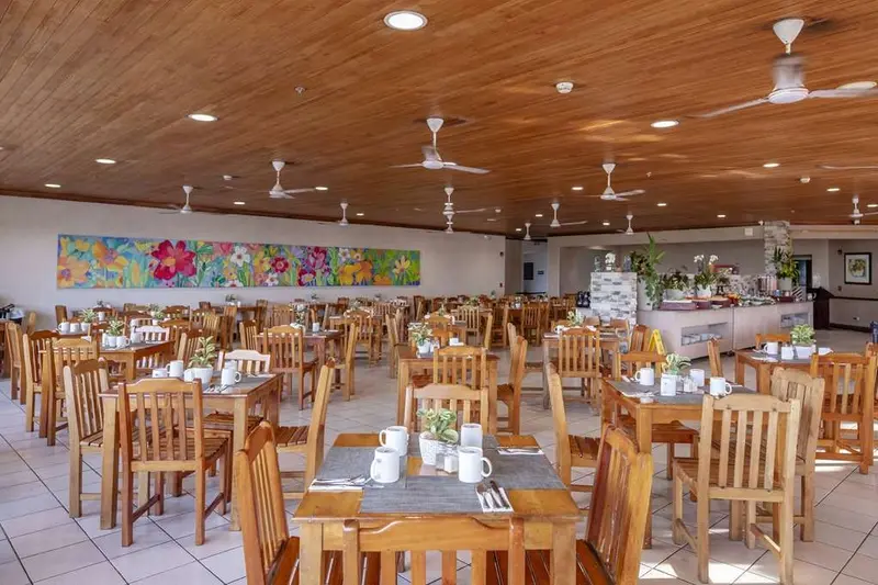 Comedor del restaurante con mesas y sillas de madera y techo de madera con ventiladores